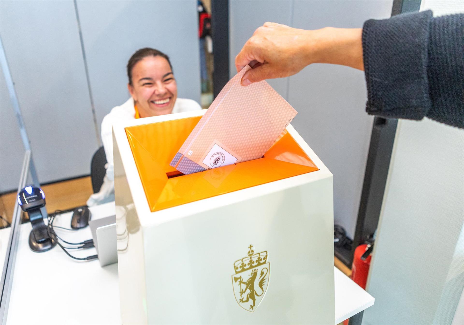 En hånd putter en stemmeseddel ned i en valgurne
