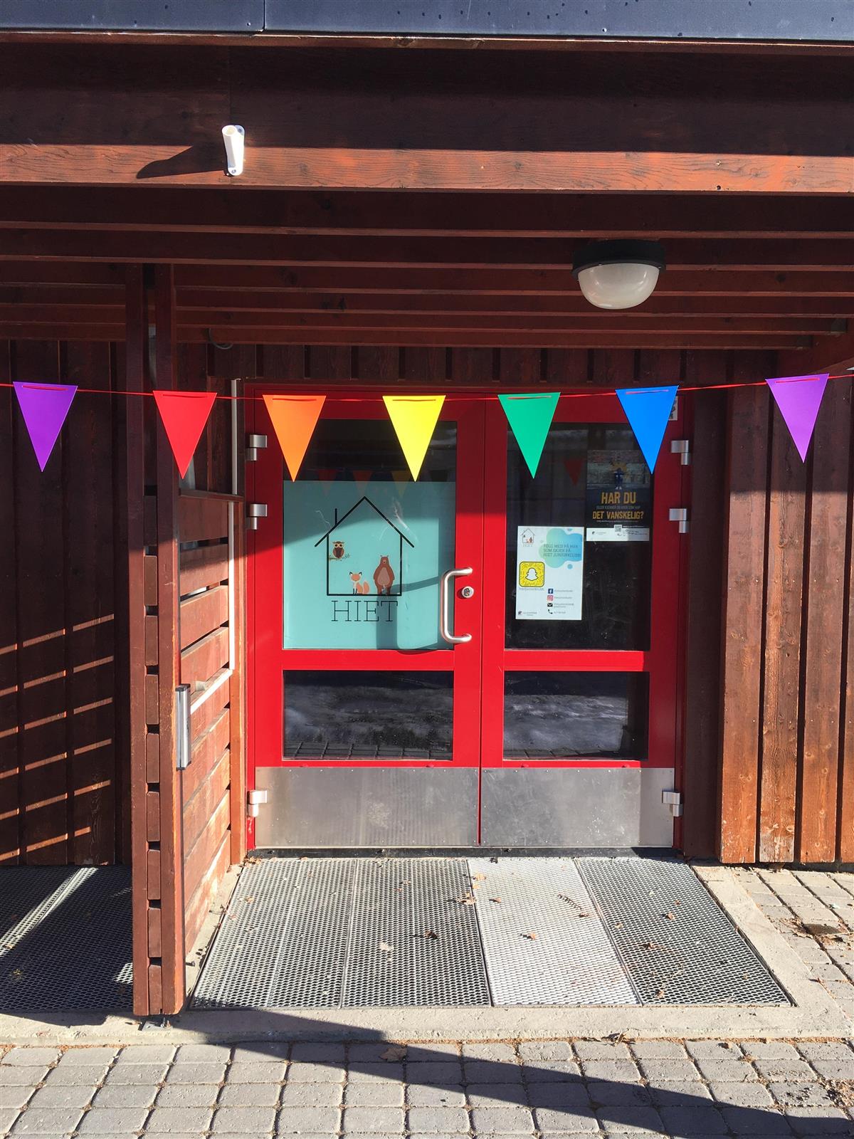 Foto av inngangspartiet på Hiet juniorklubb med en fargerik vimperekke over inngangsdøren - Klikk for stort bilde