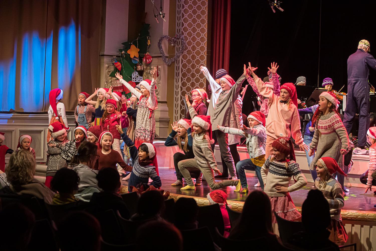 Foto av mange barn i kostymer på scenen under en juleforestilling