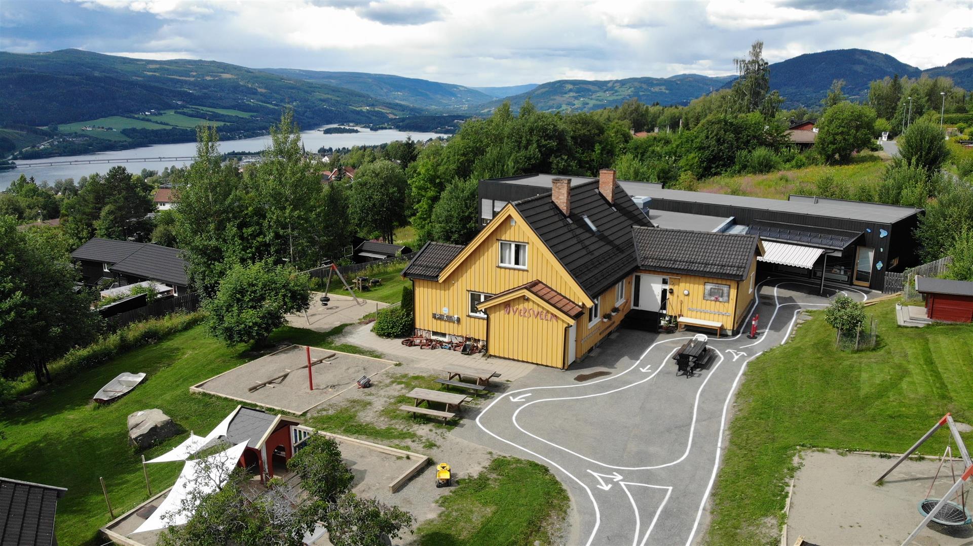 Oversiktsbilde av gult bygg og lekeplass